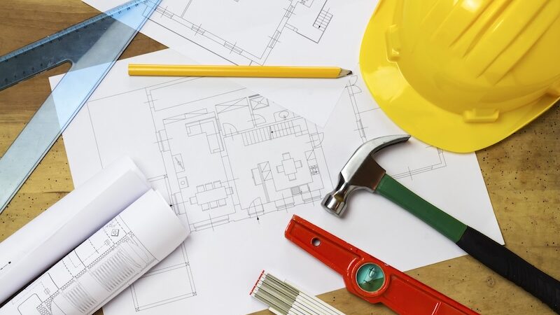 Byggritningar, hammare och skyddshjälm